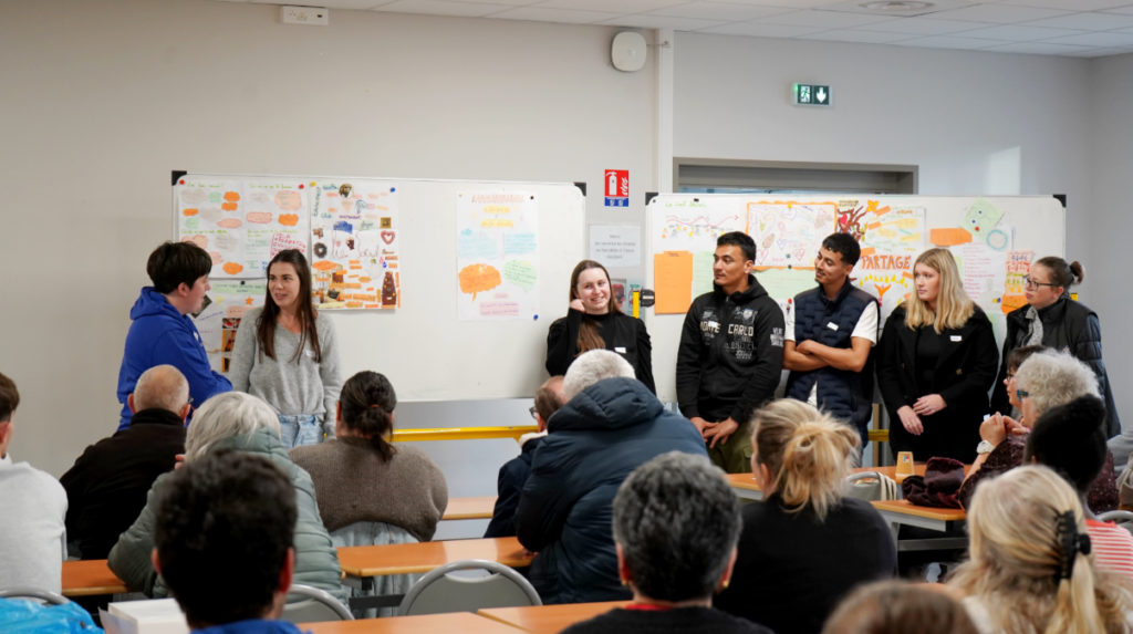 Un groupe présente son affiche devant les autres. On peut voir sur les deux tableaux blancs derrière eux, plusieurs affiches qui ont été présentées précédemment.