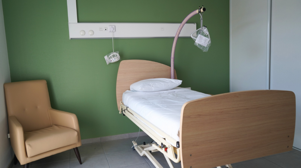 Une chambre type que l'on trouves aux Lits d'Accueil Médicalisés : un lit adapté, un fauteuil, une salle de bain. 