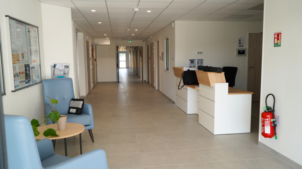 L'accueil dans le nouveau bâtiment. On y voit le bureau d'accueil, les fauteuils à l'entrée pour patienter. 